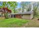 Brick house with sunroom and green lawn. Surrounded by lush greenery with blue sky and clouds at 2920 N Buck Creek Rd, Greenfield, IN 46140
