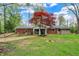 Backyard view of brick home with sunroom and unique landscaping surrounded by lush greenery at 2920 N Buck Creek Rd, Greenfield, IN 46140