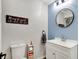 Charming bathroom with blue accent wall, round mirror, vanity, and toilet with humorous wall decor at 2920 N Buck Creek Rd, Greenfield, IN 46140