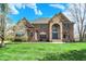Two-story brick home boasts stone accents, arched entryway, a well-manicured lawn, and professional landscaping at 3940 Woodcrest Ct, Westfield, IN 46062