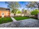 Charming backyard featuring stone patio, a brick outbuilding, lush lawn, and a wood fence at 5130 N Washington Blvd, Indianapolis, IN 46205