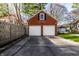 Two-car garage with brick facade and white doors, alongside a fenced yard and paved driveway at 5130 N Washington Blvd, Indianapolis, IN 46205