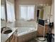 Bright bathroom featuring a corner bathtub, vanity with sink, and a large window offering ample natural light at 5773 Station Hill Dr, Avon, IN 46123