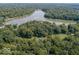 Aerial view of lush acreage with mature trees surrounding the property and a lake in the distance at 7037 Indian Lake W Blvd, Indianapolis, IN 46236