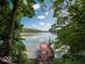 Scenic lake view with dock and American flag, surrounded by lush trees and serene water at 7037 Indian Lake W Blvd, Indianapolis, IN 46236