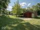 Outbuilding exterior with ample green space, framed by a white fence and mature trees offering a serene setting at 7037 Indian Lake W Blvd, Indianapolis, IN 46236