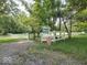 Property entrance featuring a white fence and gate surrounded by lush trees, with real estate sign at 7037 Indian Lake W Blvd, Indianapolis, IN 46236