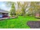 Green backyard with mature trees, a play set, and a brick house at 7756 N Audubon Rd, Indianapolis, IN 46250