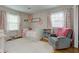 Cozy bedroom with a daybed, floral curtains, plush armchair, and a soft white rug at 7756 N Audubon Rd, Indianapolis, IN 46250