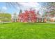 Charming brick home with a lush green lawn and a vibrant red Japanese maple tree in the front yard at 7756 N Audubon Rd, Indianapolis, IN 46250