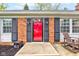 Close-up of a striking red front door framed by black shutters and surrounded by a brick facade at 7756 N Audubon Rd, Indianapolis, IN 46250