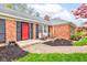 Inviting front porch with a red door, black shutters, and chairs, complemented by neat landscaping at 7756 N Audubon Rd, Indianapolis, IN 46250