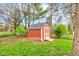 Charming red shed with white trim and a small porch, nestled in a fenced backyard area at 7756 N Audubon Rd, Indianapolis, IN 46250