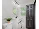 Modern bathroom with white vanity, round mirror, stylish lighting, tiled walls, and a window at 8041 Barry Rd, Indianapolis, IN 46219