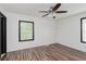 A cozy bedroom with wood-look floors, white walls, a ceiling fan, and a window view of greenery at 8041 Barry Rd, Indianapolis, IN 46219