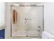 This bathroom features a shower with a glass door, white tiles, and orange towels hanging from the shower rod at 902 N College Ave, Indianapolis, IN 46202