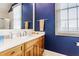Modern bathroom boasts blue walls, a wood vanity, a light countertop, and a large mirror at 902 N College Ave, Indianapolis, IN 46202