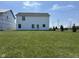 Back exterior view of the home showcasing the white siding and backyard lawn at 990 Sunchaser Rd, Lebanon, IN 46052