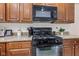 Close up of gas range, white tile backsplash and brown cabinetry in kitchen at 12821 Gloria Dr, Fishers, IN 46037