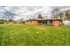 Spacious backyard featuring well-maintained lawn, a brick home with a sunroom and exterior seating area, plus mature trees at 1507 Lynnwood Dr, Anderson, IN 46012