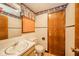 Modest bathroom featuring a single sink vanity, toilet, and a wood-paneled door at 1507 Lynnwood Dr, Anderson, IN 46012