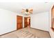 A carpeted bedroom features neutral walls, a ceiling fan, and a natural wood door at 1652 Valley Brook Dr, Indianapolis, IN 46229