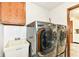 A modern laundry room features a stainless steel washer and dryer set, a utility sink, and wooden cabinets at 1652 Valley Brook Dr, Indianapolis, IN 46229