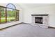 Living room showcasing a fireplace, large arched window, neutral walls, neutral carpet, and natural wood trim at 1652 Valley Brook Dr, Indianapolis, IN 46229