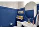Stylish half-bath with blue wainscoting, patterned wallpaper, and a gold-framed round mirror at 16683 Alex Dr, Noblesville, IN 46060