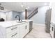 Bright kitchen featuring a large island with quartz countertop, white cabinets, and staircase in the background at 1723 Fletcher Ave, Indianapolis, IN 46203