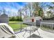 A back deck featuring a table and grill overlooking a lawn, a detached garage, privacy fence, and mature trees at 207 S Arlington Ave, Indianapolis, IN 46219