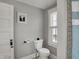 The bathroom has grey walls, a toilet, and a window with natural light to illuminate the space at 207 S Arlington Ave, Indianapolis, IN 46219