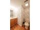 Cozy powder room featuring an oak vanity, classic wallpaper, and wood flooring at 3611 Owster Ln, Indianapolis, IN 46237