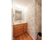 Charming powder room with oak vanity, hardwood floors, and patterned wallpaper at 3611 Owster Ln, Indianapolis, IN 46237