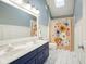 Bathroom with dual sinks, floral shower curtain and skylight allowing natural light at 3837 Penzance Pl, Carmel, IN 46032