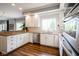 Open kitchen boasts white cabinets, modern appliances, and a scenic window overlooking the backyard at 3837 Penzance Pl, Carmel, IN 46032