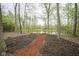 Secluded view of a tranquil pond, accessible by a mulched walking path through wooded area at 3837 Penzance Pl, Carmel, IN 46032