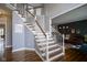 Elegant staircase with hardwood steps, white railing, and a glimpse of the living room at 3837 Penzance Pl, Carmel, IN 46032