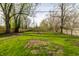 Large backyard featuring a grassy area, bordered by a wooden fence and mature trees at 3909 Aloda St, Indianapolis, IN 46203