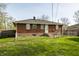 Exterior shot of a brick home, with a grassy backyard enclosed by a chain-link fence at 3909 Aloda St, Indianapolis, IN 46203
