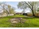 Backyard view with a brick firepit in the center, green grass, and wooden fences around the perimeter at 3909 Aloda St, Indianapolis, IN 46203