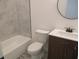 Bright bathroom features a white vanity, toilet, bathtub and shower with marble tile surround at 4230 Kingsley Dr, Indianapolis, IN 46205