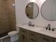 Stylish bathroom with dual sinks, marble countertops, round mirrors and a tiled shower at 4230 Kingsley Dr, Indianapolis, IN 46205