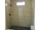 Modern walk-in shower features bronze fixtures, tiled walls and a black, hexagon-tiled shower floor at 4230 Kingsley Dr, Indianapolis, IN 46205