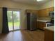 Bright kitchen with stainless steel appliances, wood cabinets, and sliding glass doors leading to the backyard at 4932 Tuscany Ln, Indianapolis, IN 46254
