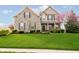 Charming two-story home with a stone facade, manicured lawn, and a blossoming tree at 5196 E County Road 100 S, Avon, IN 46123