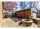 Brick paved backyard with brick building, and firepit under a blue sky, bordered by privacy fence and mature trees at 5331 N New Jersey St, Indianapolis, IN 46220