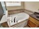 Bathroom featuring a large soaking tub with a tile surround and a window for natural light at 5549 Dill Ct, Indianapolis, IN 46237