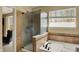 Bathroom highlighting a glass-enclosed shower, soaking tub, tile accents, and natural light from the window at 5549 Dill Ct, Indianapolis, IN 46237