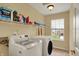 Bright laundry room with modern washer and dryer, overhead shelving, and a window offering a pleasant view at 5549 Dill Ct, Indianapolis, IN 46237
